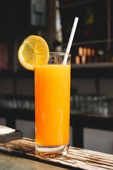 Juicy orange juice in a tall glass with fresh orange slice