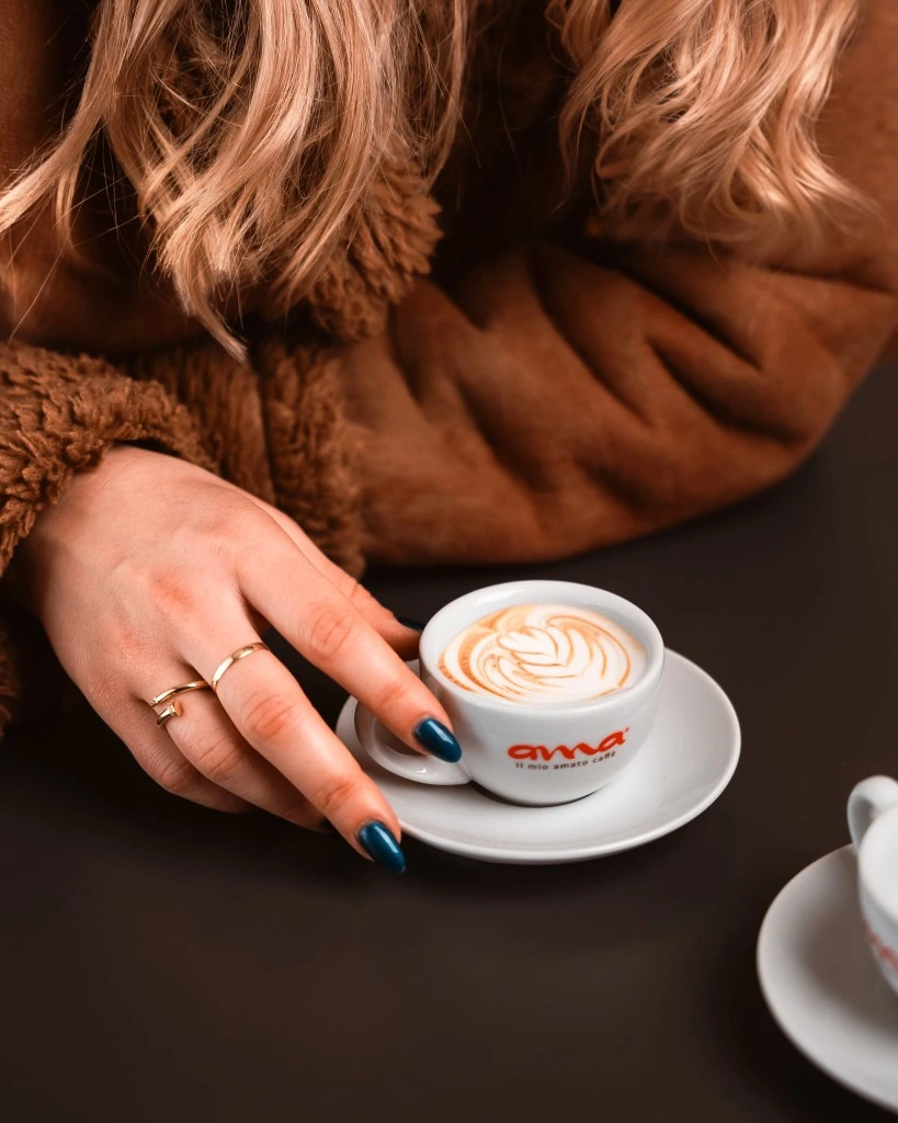 Ama Caffè cappuccino with latte art at a cafe table