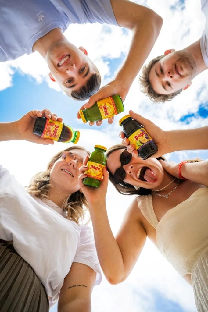 Friends sharing Pago fruit juice bottles outdoors