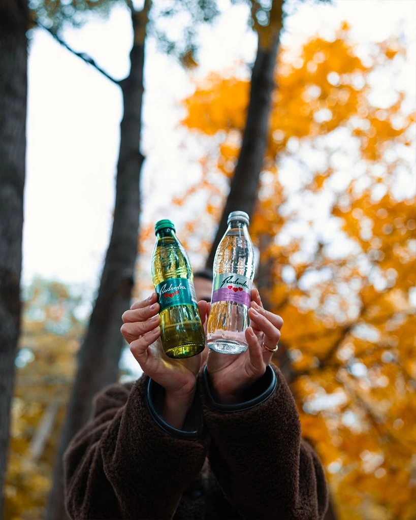 Radenska glass bottles held in an autumn forest